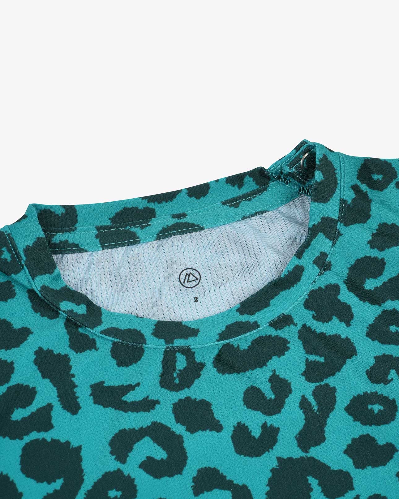 Nahaufnahme eines Aina Kinder UV-Shirts von Main Design in Blaugrün mit schwarzem Leopardenmuster. Es verfügt über einen Rundkragen und ein kleines Größenetikett. Das dehnbare, bequeme und schnelltrocknende Material bietet LSF 50+ Schutz für sonnige Abenteuer.
