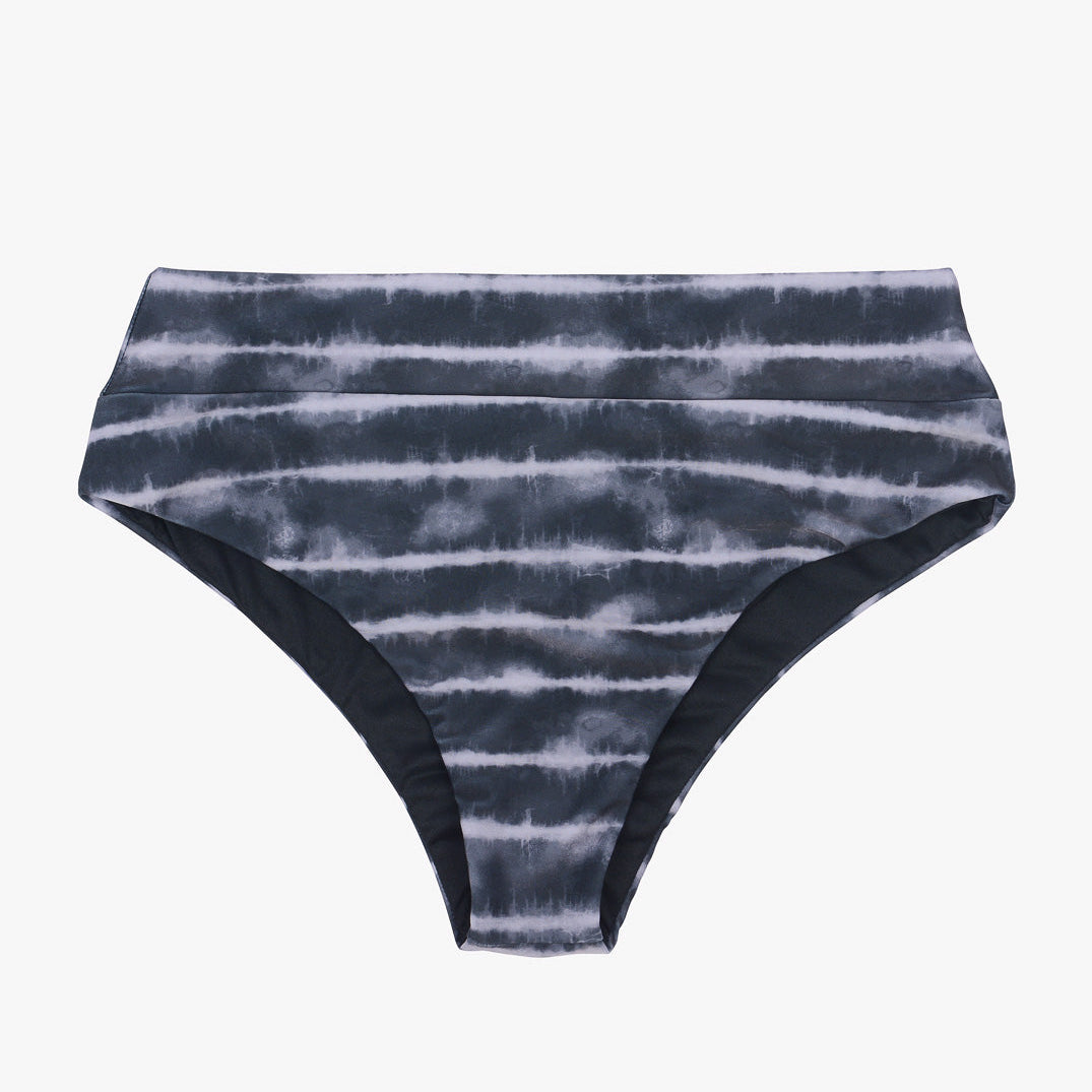 Ein Paar Bikinihosen für Damen mit hoher Taille und einem schwarz-weißen Batikmuster. Der Stoff wirkt glatt und leicht glänzend, und die Hose hat ein einfaches, nahtloses Design mit mäßiger Bedeckung, perfekt für alle, die eine modische und dennoch nachhaltigere Bikini-Option suchen, Alice Bikinihose von Main Design.