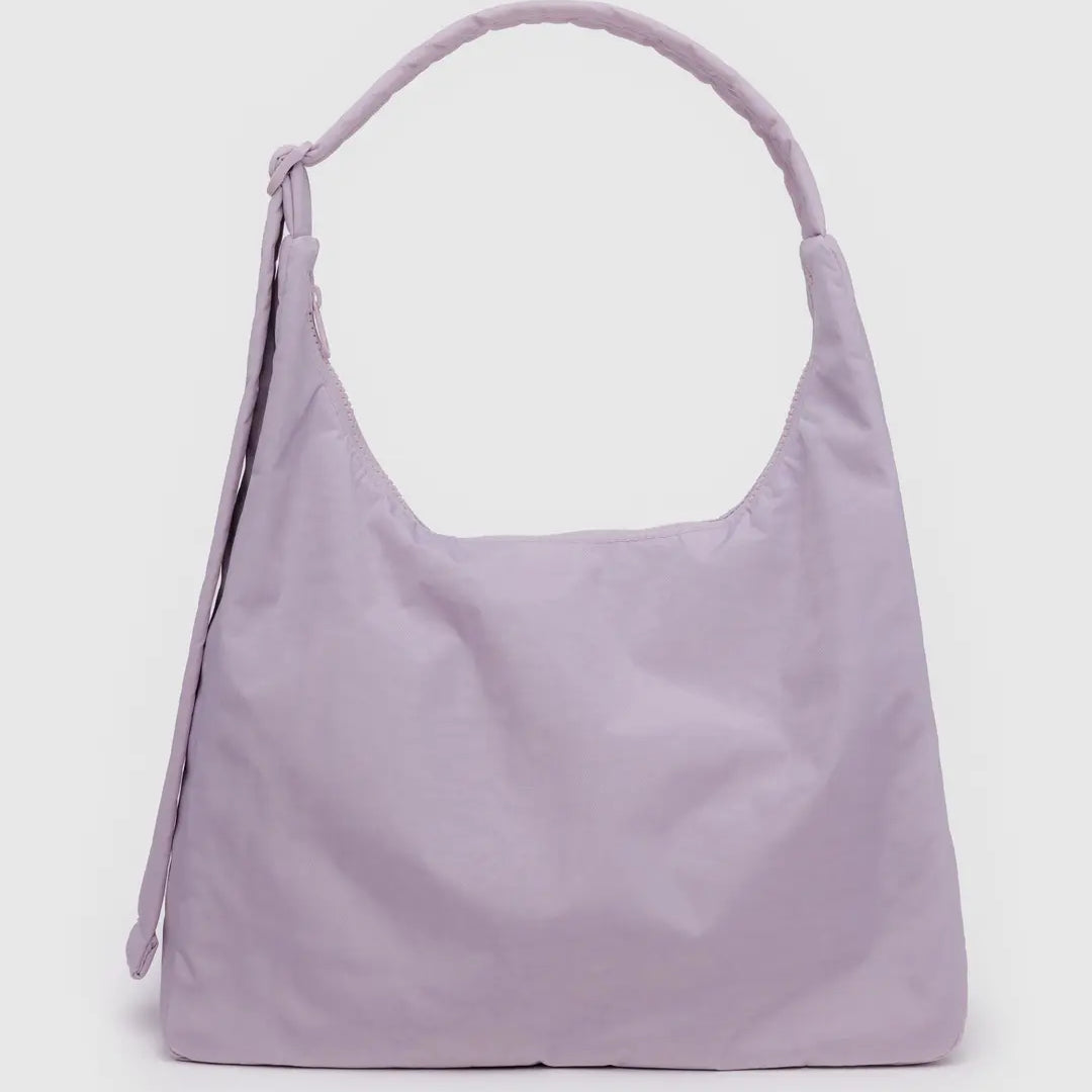 Die BAGGU Nylon-Umhängetasche in zartem Pastelllavendel hat einen einzelnen breiten Riemen und ein minimalistisches Design, das sich vor einem schlichten hellgrauen Hintergrund zeigt.