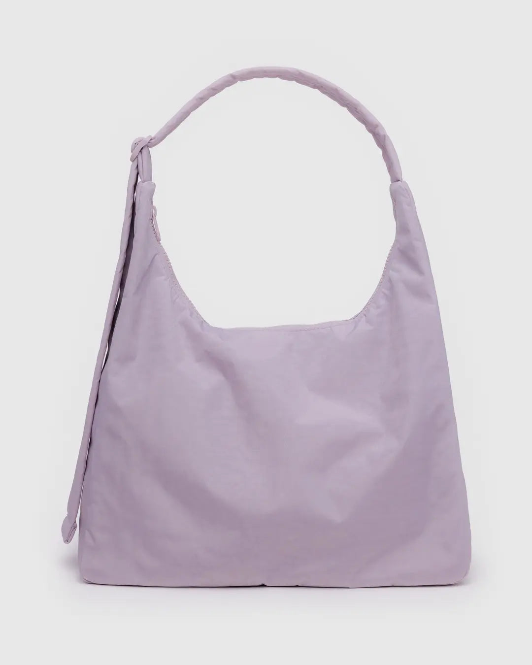 Die BAGGU Nylon-Umhängetasche in zartem Pastelllavendel hat einen einzelnen breiten Riemen und ein minimalistisches Design, das sich vor einem schlichten hellgrauen Hintergrund zeigt.