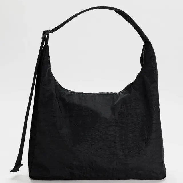 Die BAGGU Nylon Shoulder Bag von BAGGU besticht durch ihr minimalistisches Design, einen breiten Riemen und eine Seitenschleife aus strukturiertem Nylon - der stilvolle und nachhaltige Begleiter für jeden Tag.