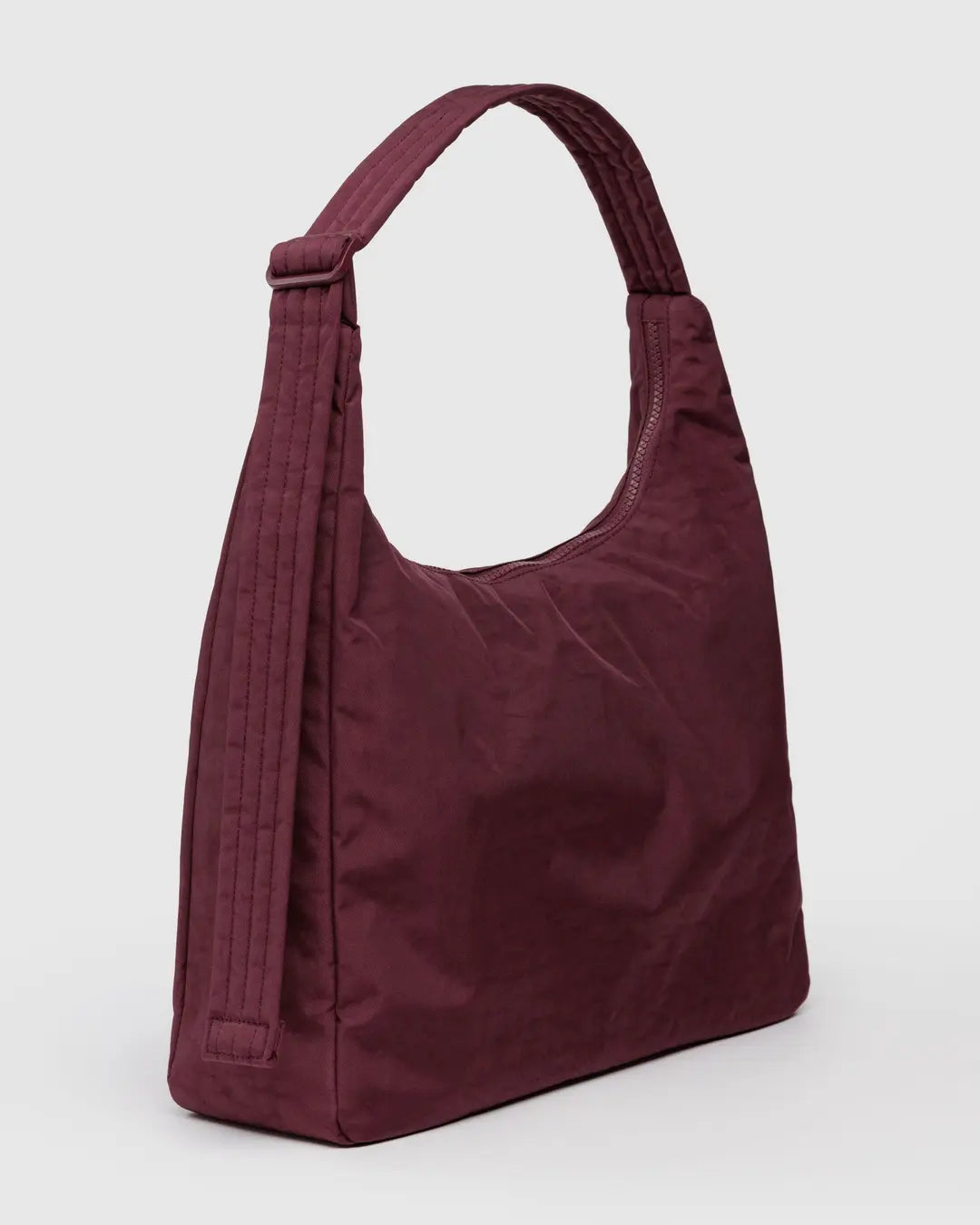 Die BAGGU Nylon Shoulder Bag in kastanienbraun zeichnet sich durch einen breiten, gesteppten Riemen und ein minimalistisches Design aus, das sich vor einem hellgrauen Hintergrund zeigt - perfekt für einen nachhaltig inspirierten Stil.
