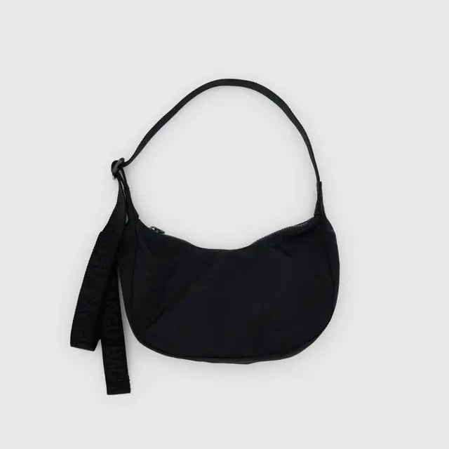 Die BAGGU Small Nylon Crescent Bag in klassischem Schwarz aus recyceltem Nylon verfügt über einen kurzen Trageriemen und ein zusätzliches Stoffband an der Seite - ideal für umweltbewusste Einkäufer. Abgebildet vor einem hellgrauen Hintergrund.