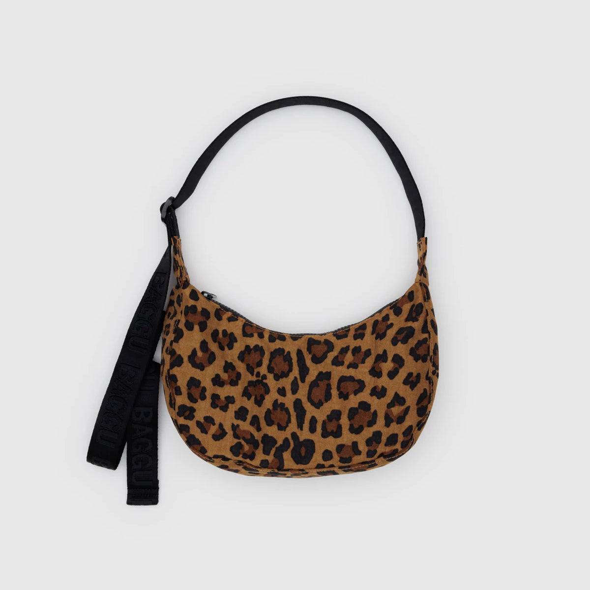 Die BAGGU Small Nylon Crescent Bag ist eine kompakte, halbmondförmige Umhängetasche von BAGGU aus recyceltem Nylon mit braunem und schwarzem Leopardenmuster, schwarzem Riemen und Schlüsselanhänger - ideal für umweltbewusste Fashionistas.