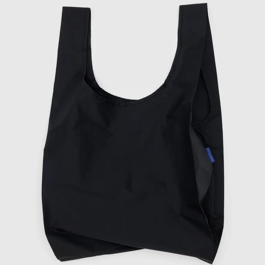 Die BAGGU Standard Tragetasche von BAGGU ist aus recyceltem Ripstop-Nylon gefertigt, hat breite, kurze Henkel und ein kleines blaues Seitenetikett. Präsentiert vor hellem grauem Hintergrund.