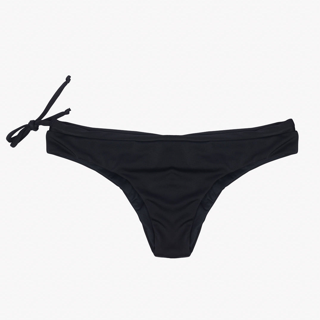 Ein Paar Main Design Blush Surf Bikinihosen in Schwarz ist vor einem schlichten, weißen Hintergrund abgebildet. Der nachhaltige Bikini verfügt über ein seitliches Bindedetail auf der linken Seite und ist aus umweltfreundlichem Stoff gefertigt.