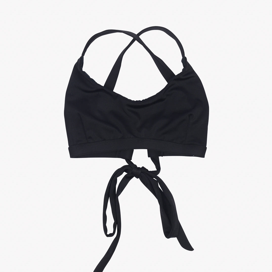 Das Bild zeigt ein Charm Surf Bikini Oberteil von Main Design mit überkreuzten Trägern vorne und einem Bindeverschluss hinten. Der Stoff wirkt glatt und das Design ist schlicht und doch stilvoll.