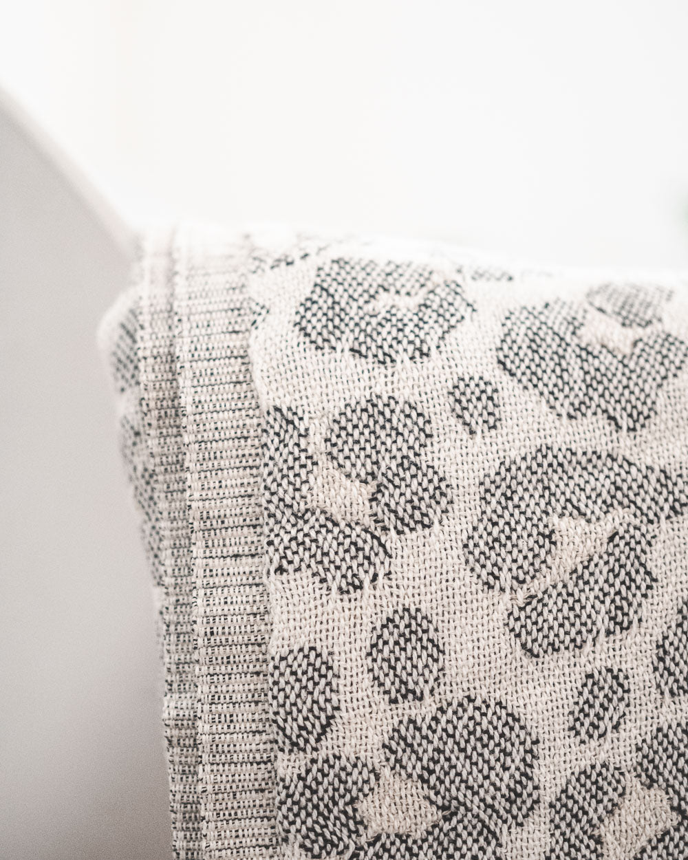 Eine Nahaufnahme des hellen Stoffes mit grauem Leopardenmuster, drapiert über Weiß - perfekt, um Ihrem Raum mit der gemütlichen Main Design Decke Savanna ein subtiles Flair zu verleihen.