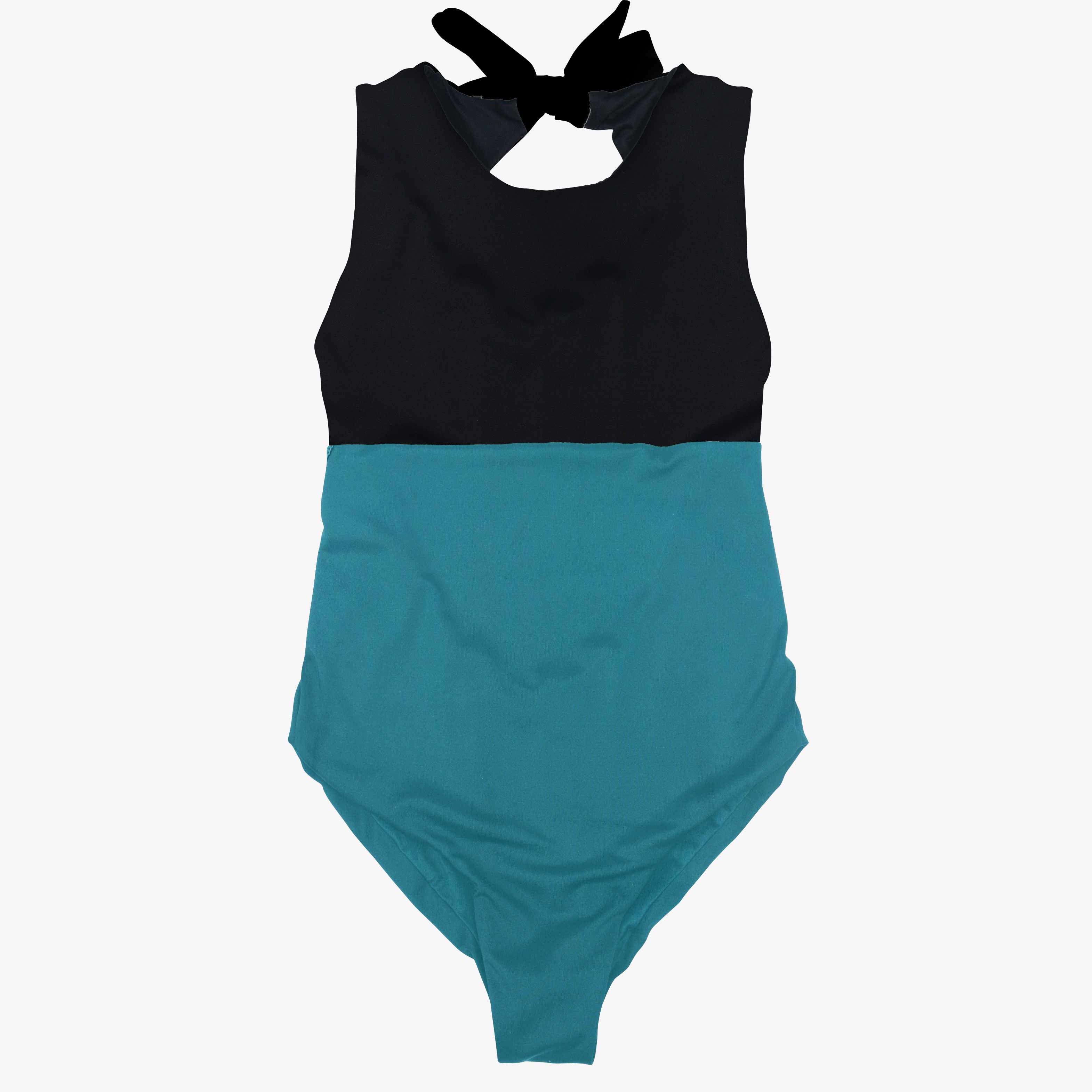 Der Divine Surf Badeanzug von Main Design ist ein ärmelloser Surfanzug mit einem auffälligen zweifarbigen Design: einem schwarzen Oberteil und einem türkisfarbenen Unterteil. Er hat einen hohen Ausschnitt, einen schwarzen Bindeverschluss am Rücken und ist aus umweltfreundlichem Stoff für umweltbewusste Schwimmer gefertigt.