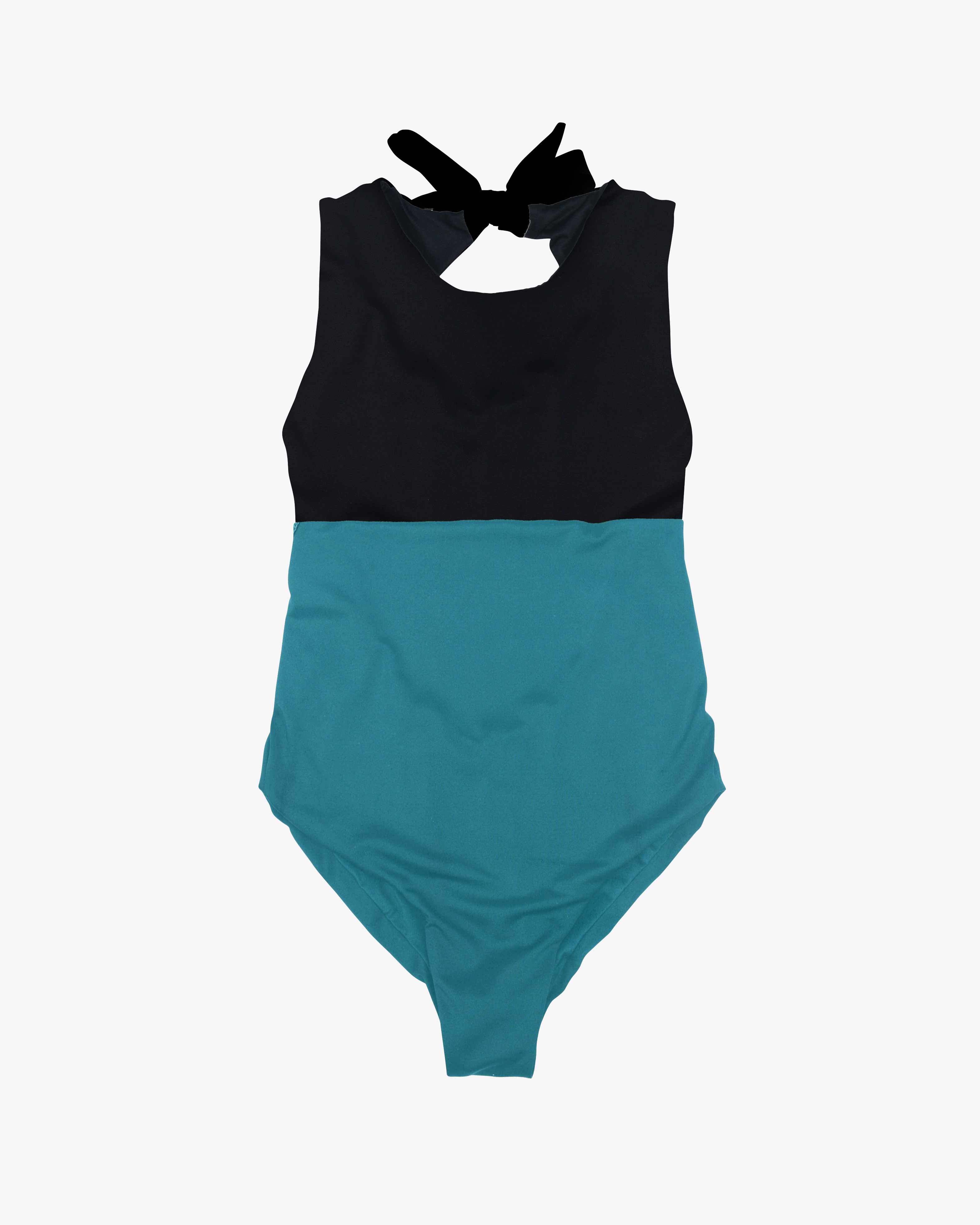 Der Divine Surf Badeanzug von Main Design ist ein ärmelloser Surfanzug mit einem auffälligen zweifarbigen Design: einem schwarzen Oberteil und einem türkisfarbenen Unterteil. Er hat einen hohen Ausschnitt, einen schwarzen Bindeverschluss am Rücken und ist aus umweltfreundlichem Stoff für umweltbewusste Schwimmer gefertigt.