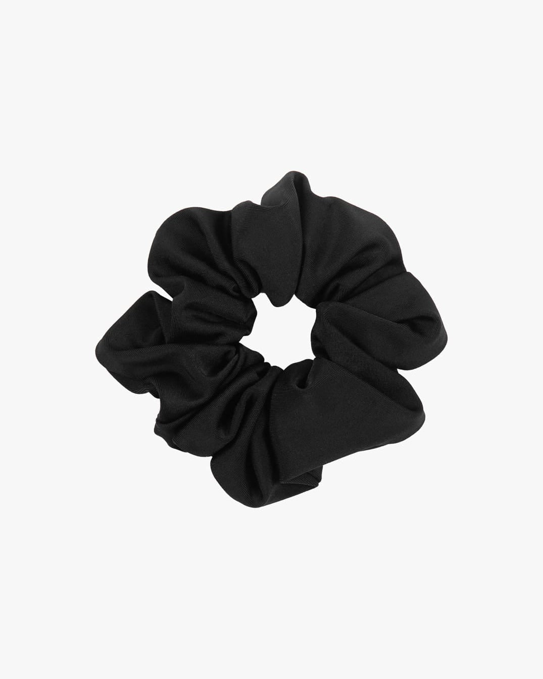 Ein einfarbiges Haargummi aus schwarzem Stoff von Main Design ist auf einem schlichten weißen Hintergrund abgebildet. Das Haargummi ist kreisförmig gerafft, wobei sich der gerüschte Stoff nach außen erstreckt, was das Engagement für nachhaltige Modeentscheidungen unterstreicht.