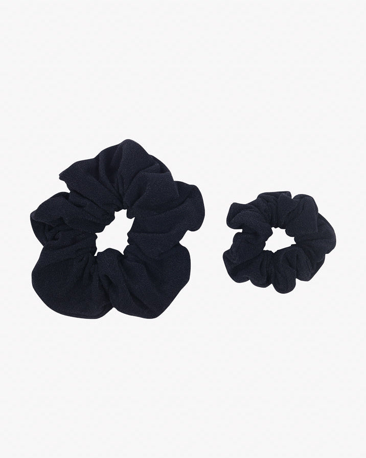 Zwei schwarze Haargummis aus recyceltem Stoff sind auf weißem Hintergrund platziert. Ein Haargummi ist deutlich größer als das andere, wodurch ein Größenvergleich möglich wird. Beide Haargummis mini von Main Design haben eine geraffte, gekräuselte Optik.