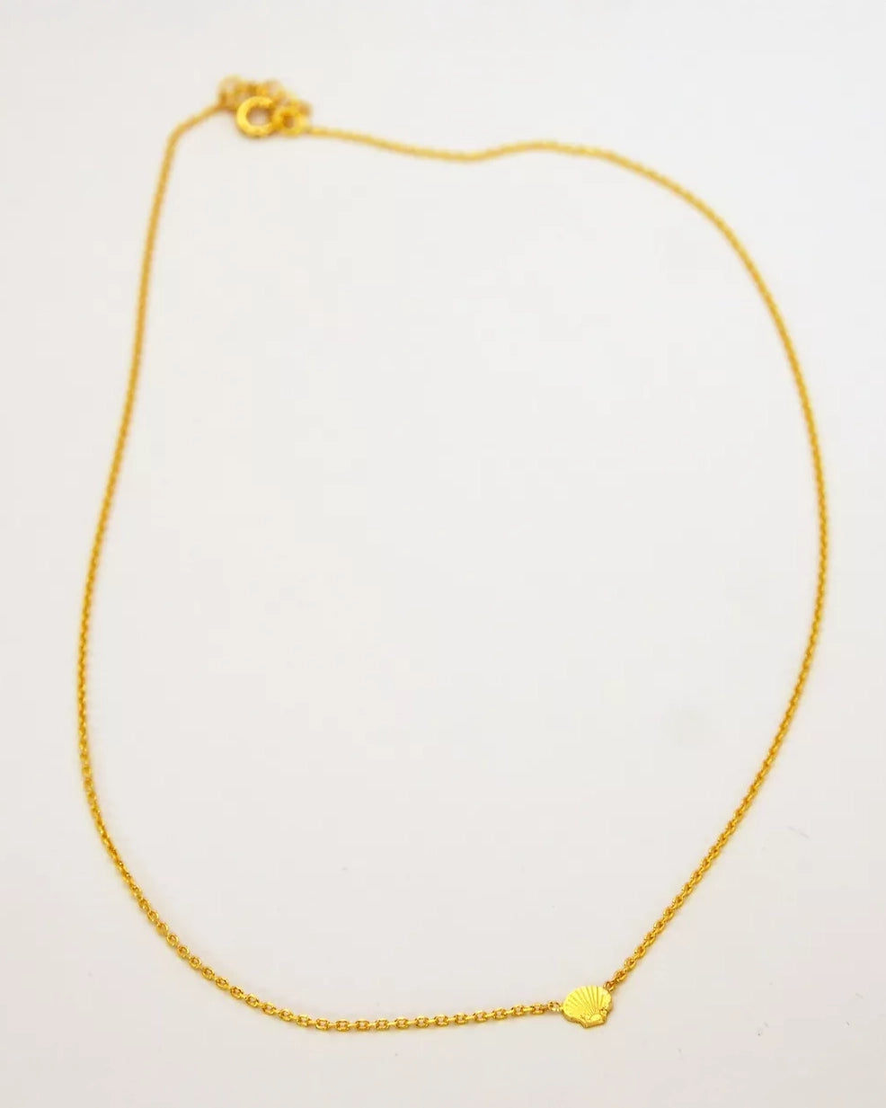 Die Halskette von Adorabili der Marke Adorabili aus 24K vergoldetem Gold mit einem kleinen muschelförmigen Anhänger ist auf schlichtem weißem Hintergrund zu sehen.