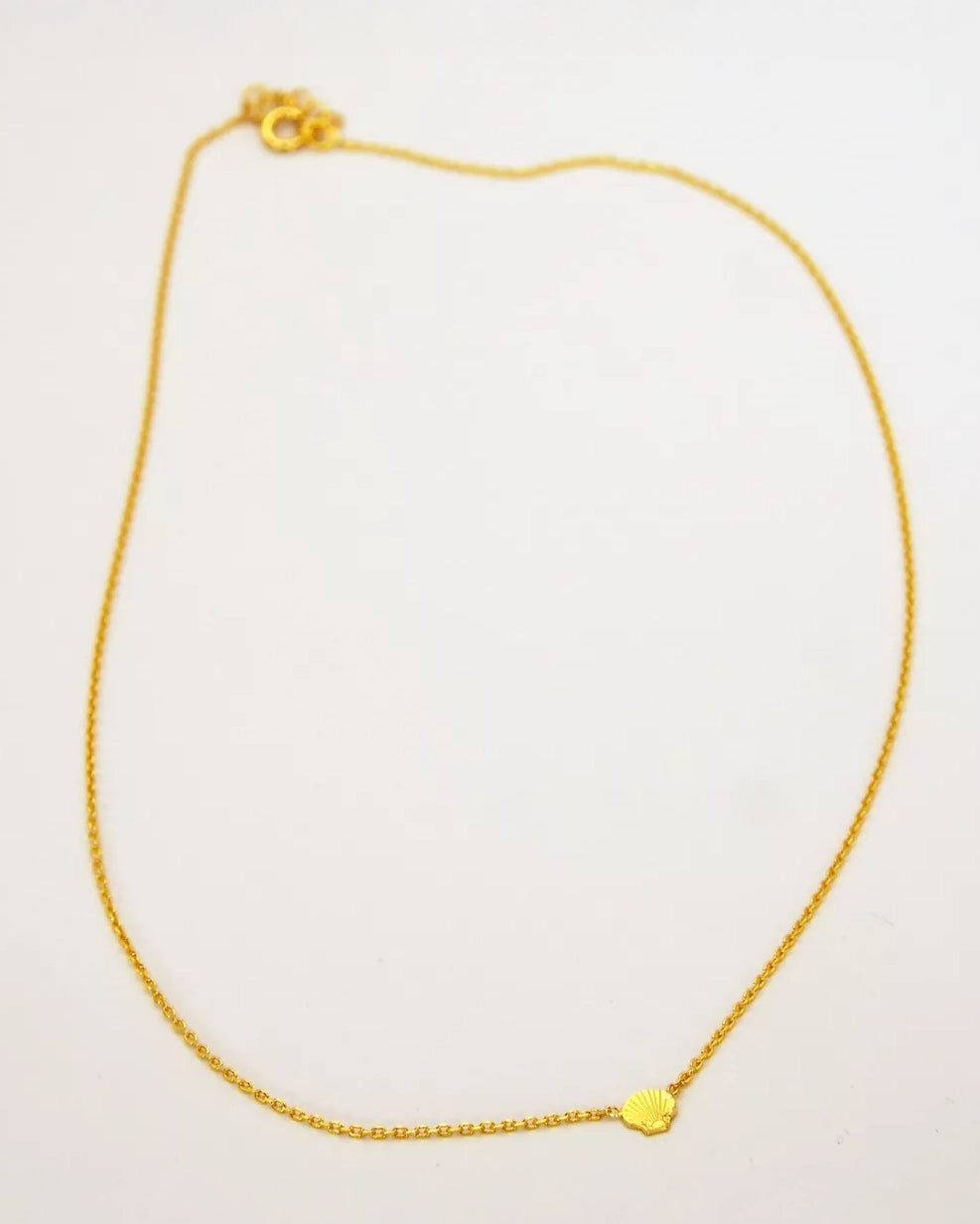 Die Halskette von Adorabili der Marke Adorabili aus 24K vergoldetem Gold mit einem kleinen muschelförmigen Anhänger ist auf schlichtem weißem Hintergrund zu sehen.