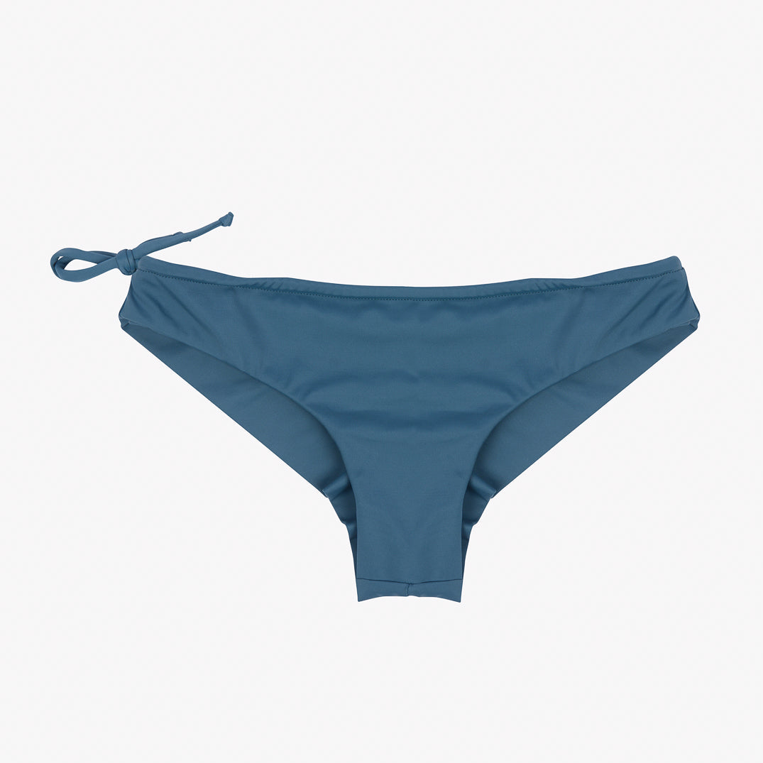 Ein blaugrünes Bikinihöschen mit einem Bindedetail auf einer Seite, aus einem glatten Stoff, der für Badebekleidung entworfen wurde. Diese Keira Surf Bikinihose von Main Design bietet ein nahtloses Design für ultimativen Komfort. Der Hintergrund ist schlicht weiß.