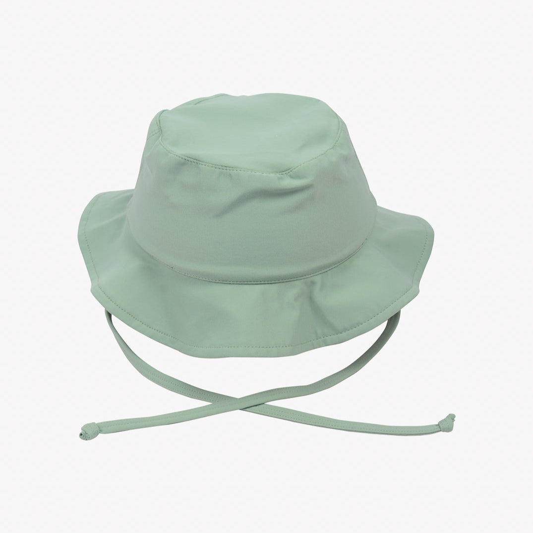 Ein hellgrüner Kinder-Sonnenhut von Main Design ist auf einem schlichten weißen Hintergrund abgebildet. Der Hut hat eine breite Krempe und Kinnriemen, die an den Enden gebunden werden und beim Tragen für zusätzliche Sicherheit sorgen. Er ist aus umweltfreundlichem Stoff mit LSF 50+ gefertigt und sorgt dafür, dass Ihr Kind in der Sonne sicher ist.