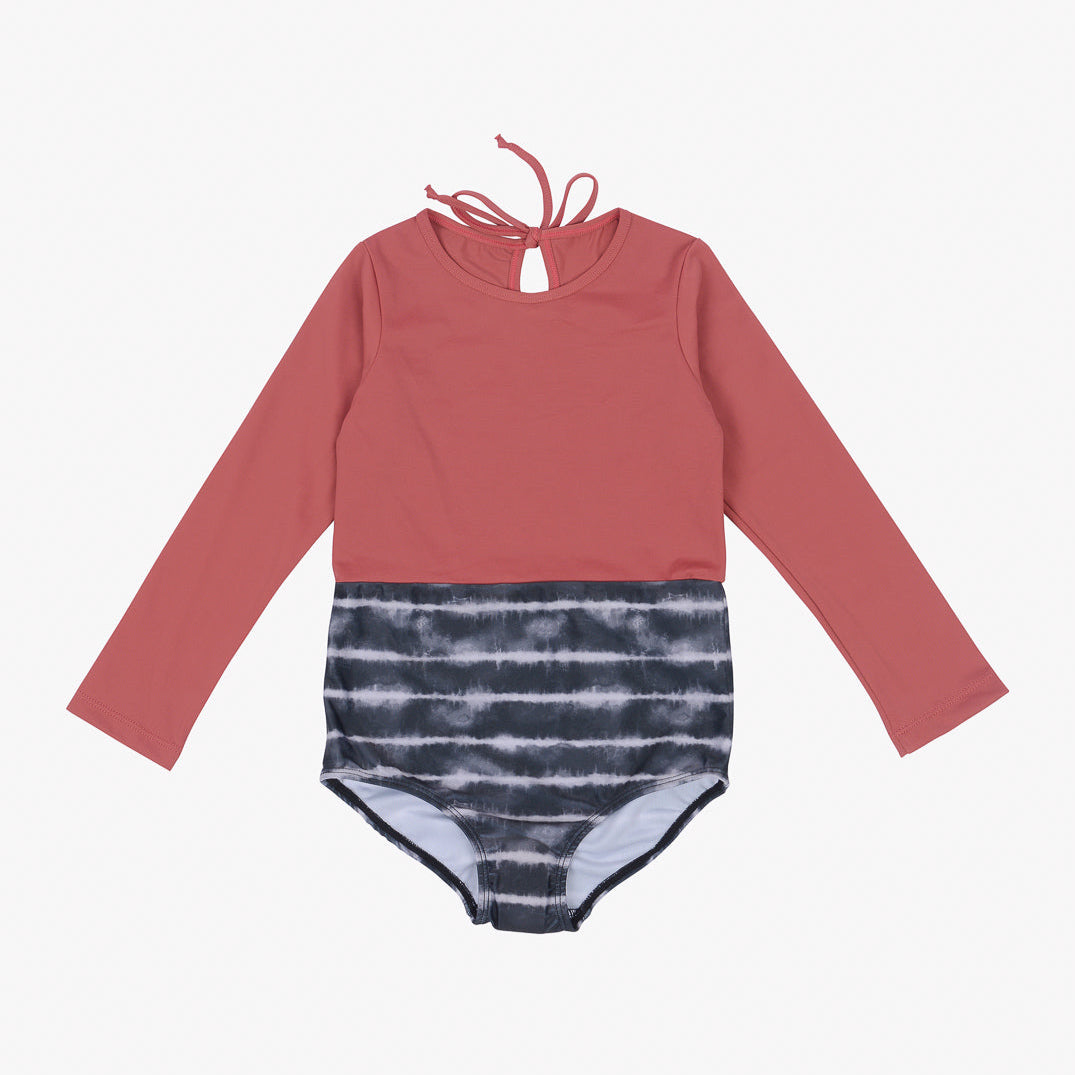 Langärmliger einteiliger Badeanzug für Kinder, Laila Mädchen Badeanzug von Main Design, mit Schlüsselloch und Bindeverschluss am Hals. Die obere Hälfte ist einfarbig rosa und die untere Hälfte weist ein schwarz-weißes Batikmuster auf. Er ist aus umweltfreundlichem Stoff gefertigt und bietet außerdem Sonnenschutz mit LSF 50+ für zusätzlichen Schutz.