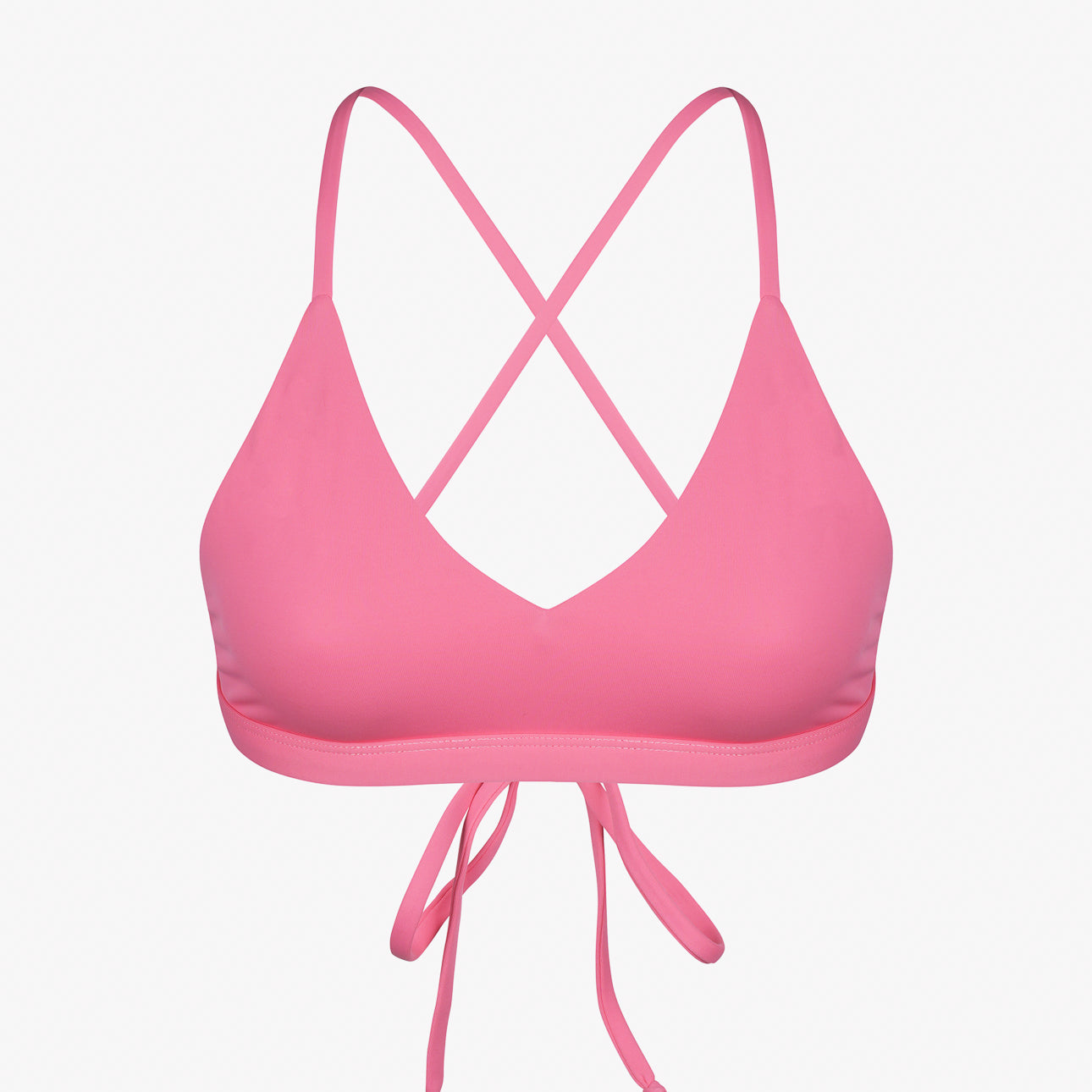 Das rosa Pasta-Bikini-Oberteil von Main Design hat dünne, überkreuzte Träger auf der Rückseite und eine Schleife vorne. Es besteht aus glattem, dehnbarem, chlorbeständigem Stoff und recycelten Materialien für eine bequeme Passform vor dem schlichten weißen Hintergrund.