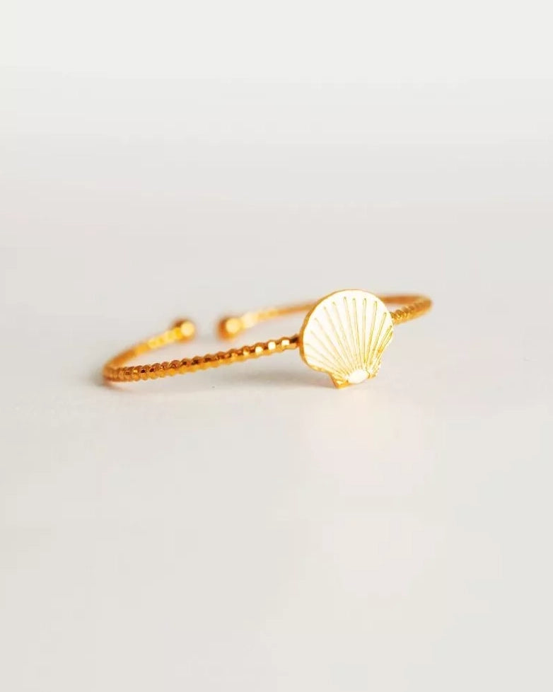 Der Ring von Adorabili ist ein zarter Goldring mit strukturierter Ringschiene und kleinem Muschel-Anhänger, handgefertigt in Frankreich von der Marke Adorabili, präsentiert auf weißem Hintergrund.