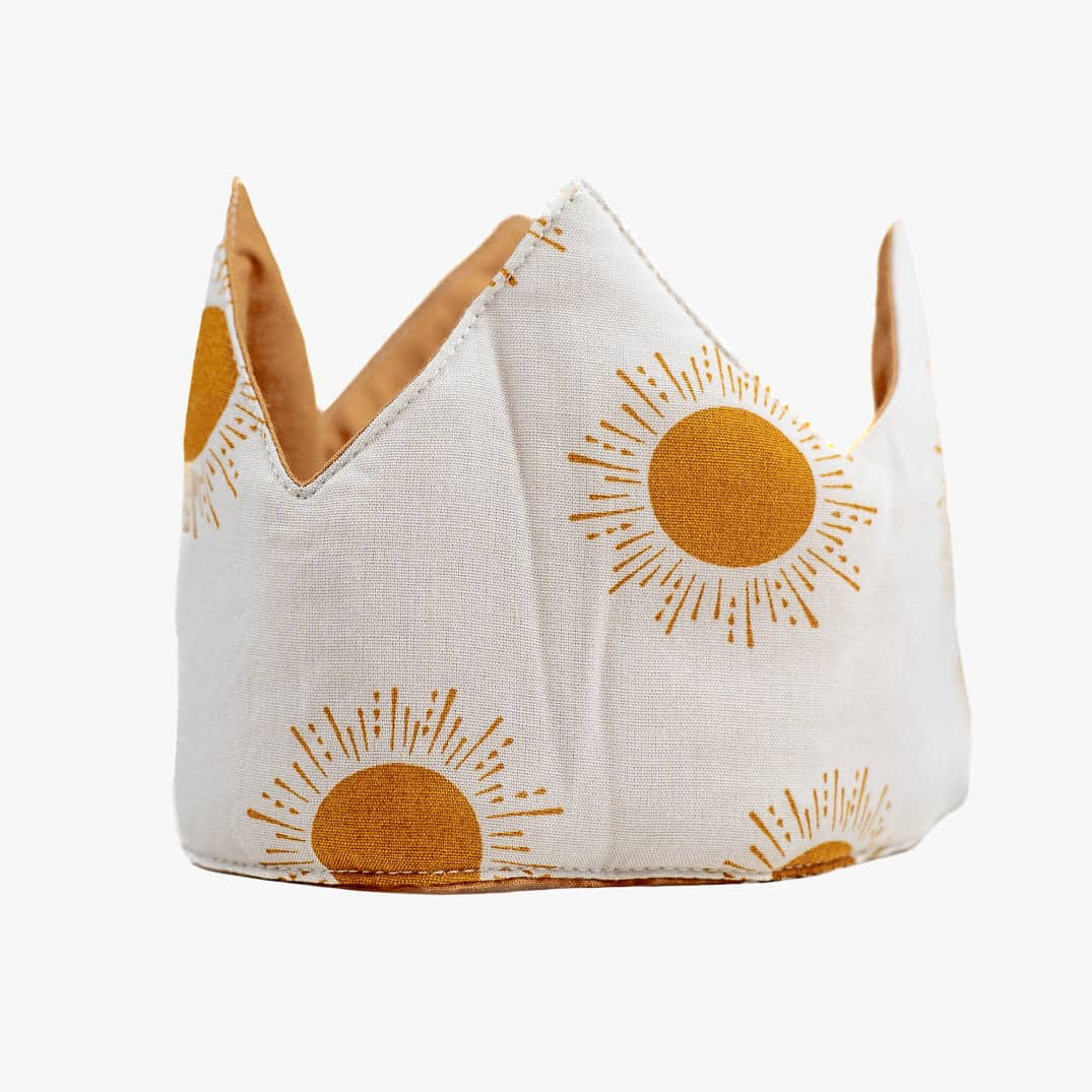 Die Stoffkrone von Several Needs reversibel von Main Design ist eine handgefertigte Stoffkrone für Kinder mit einer weißen Basis mit orangefarbenen Sonnenstrahlen, spitzen Spitzen und weicher Polsterung - mit Sorgfalt in Bali hergestellt.