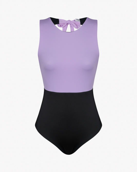 Tauchen Sie ein in den Divine Surf Badeanzug von Main Design aus umweltfreundlichem Material. Dieser ärmellose, zweifarbige Badeanzug besteht aus einem lila Oberteil und einem schwarzen Unterteil mit Rundhalsausschnitt und einer stylischen Schleife am Rücken – ideal zum Wellenreiten und gleichzeitig nachhaltig!.