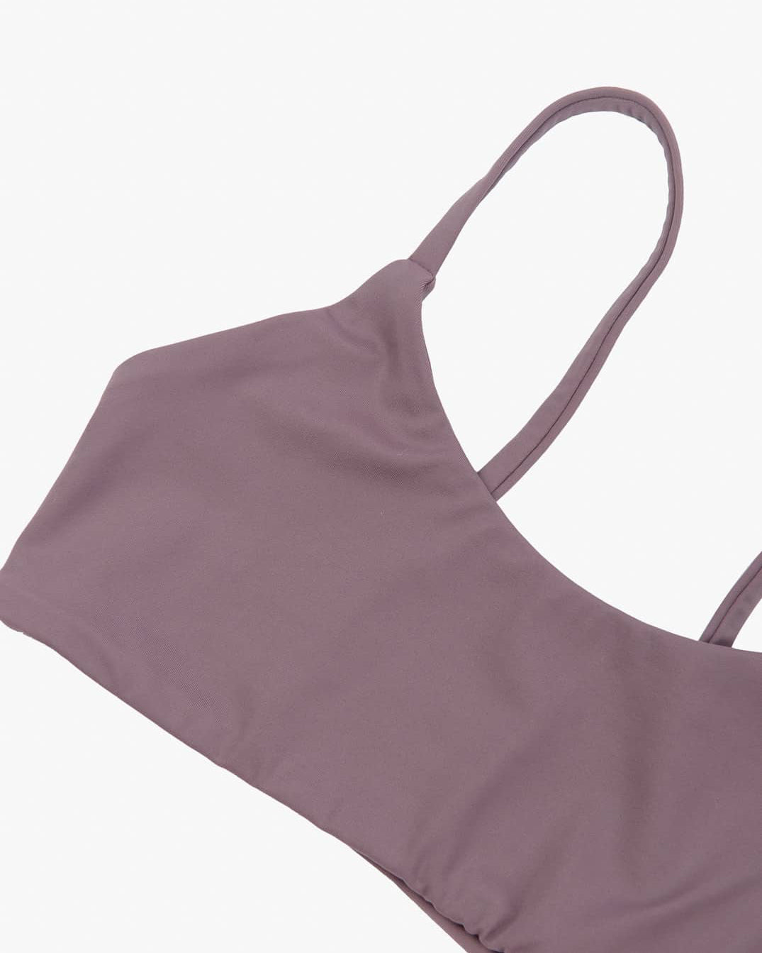 Ein malvenfarbenes „Sassy“-Bikinioberteil von Main Design mit minimalistischem, nahtlosem Design mit dünnen Trägern und aus recycelten Materialien wird flach auf einem weißen Hintergrund präsentiert.