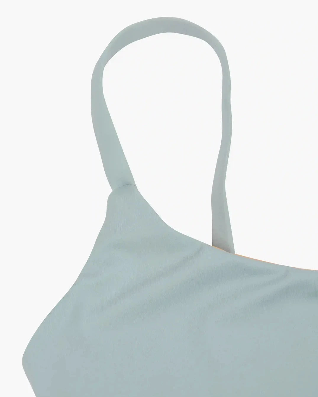 Nahaufnahme eines hellblauen Stoffes mit einem dünnen Schulterriemen, der wahrscheinlich zum wendbaren Sassy Bikini Oberteil von Main Design gehört, das aus nachhaltigen Materialien gefertigt ist und sich vor einem schlichten weißen Hintergrund befindet.