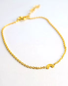 Das Armband von Adorabili ist ein zartes, handgefertigtes Schmuckstück aus 24K vergoldetem Feingold mit einem kleinen Regenbogen-Charm in der Mitte - perfekt für Kinder und präsentiert auf weißem Hintergrund.