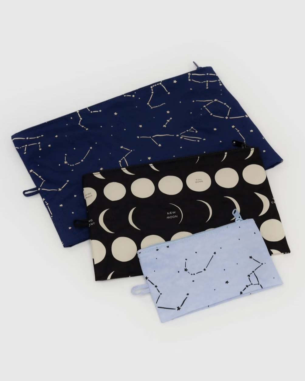 Das BAGGU Go Pouch Set besteht aus drei rechteckigen, recycelten Nylontaschen in verschiedenen Größen mit Kordelzug und astronomischen Motiven: marineblau mit Sternbildern, schwarz mit Mondphasen und hellblau mit Sternbildern.