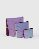 Drei farbige BAGGU Go Pouch Set Allzwecktaschen von BAGGU in verschiedenen Größen sind auf einem unifarbenen Hintergrund abgebildet und zeigen Pastell- und kräftige Farbtöne - Lavendel, Gelb, Braun, Blau und Rot - aus recyceltem Nylon.