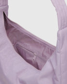 Nahaufnahme der BAGGU Nylon-Umhängetasche in Hellviolett, mit einer Innentasche mit Reißverschluss und einem teilweise geöffneten Hauptreißverschluss, der das Stofffutter sichtbar macht.