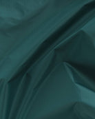 Die zerknitterte und faltige dunkelgrüne Stofftextur mit leichtem Glanz erzeugt ein Muster aus Falten und Schatten, das an das recycelte Ripstop-Nylon erinnert, das in der BAGGU Standard Tragetasche von Main Design verwendet wird.