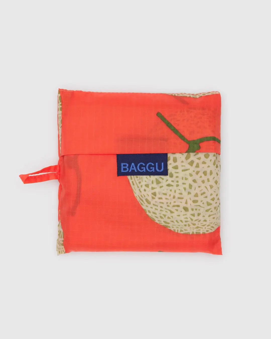 Eine gefaltete, quadratische BAGGU Standard Tragetasche in Orange mit Cantaloupe-Aufdruck und blauem BAGGU-Label auf der Vorderseite, hergestellt aus recyceltem Ripstop-Nylon von BAGGU, abgebildet auf einem schlichten hellgrauen Hintergrund.