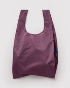 Die BAGGU Standard-Tragetasche von BAGGU ist aus recyceltem Ripstop-Nylon in Lila gefertigt, verfügt über breite Henkel und eine leicht glänzende Oberfläche und besteht aus nachhaltigen Materialien. Präsentiert vor weißem Hintergrund.