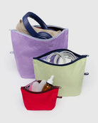 Drei Stofftaschen mit Reißverschluss aus dem BAGGU Go Pouch Set von Main Design in lila, grün und rot aus recyceltem Nylon bieten Platz für Kopfhörer mit einem beigen Tuch, Kabel und zwei kleine Flaschen auf einem schlichten hellen Hintergrund.