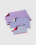 Drei rechteckige Stoffbeutel in verschiedenen Größen und Farben aus dem Main Design BAGGU Go Pouch Set, jeweils mit Reißverschluss und kontrastierendem Futter, sind auf einem schlichten hellen Hintergrund angeordnet. Hergestellt aus recyceltem Nylon.