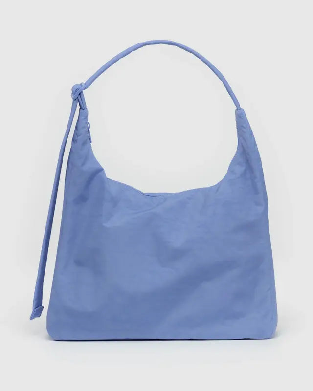 Die BAGGU Nylon-Umhängetasche von Main Design ist himmelblau mit einem einfachen strukturierten Design aus nachhaltigen Materialien. Sie verfügt über einen einzelnen Riemen, der an einem Ende geknotet ist, für einen lässigen Look, und ihr weicher Stoff bietet ein entspanntes, geräumiges Erscheinungsbild vor einem schlichten weißen Hintergrund.