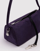 Die BAGGU Nylon Loaf Bag von BAGGU ist eine kleine, rechteckige, dunkelviolette Umhängetasche mit einem Reißverschluss oben. Ein schwarzer Riemen mit silbernen Schlüsseln und einem runden Metallanhänger ziert die Seite dieses stylischen, recycelten Accessoires.