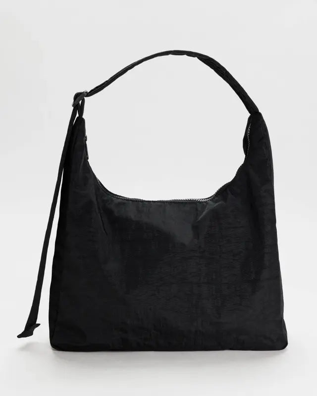 Die Nylon-Umhängetasche BAGGU von Main Design hat eine schwarze strukturierte Oberfläche, nachhaltige Materialien, einen gebogenen oberen Griff, einen Reißverschluss und eine dekorative Schleife. Sie sieht elegant vor einem schlichten weißen Hintergrund aus.