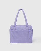Die lavendelfarbene BAGGU Small Cloud Carry-On Tasche von Main Design besteht aus recyceltem Nylon, hat zwei lange Griffe und zwei Vordertaschen, die auf einem hellgrauen Hintergrund abgebildet sind. Ideal als 16-Zoll-Laptoptasche oder als Reisetasche unter dem Sitz.
