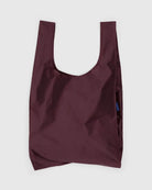 Die BAGGU Standard Tragetasche von Main Design besteht aus recyceltem Ripstop-Nylon in dunkelroter Farbe, hat breites Henkel-Design und schlichtes Aussehen und ist vor einem hellen Hintergrund präsentiert.