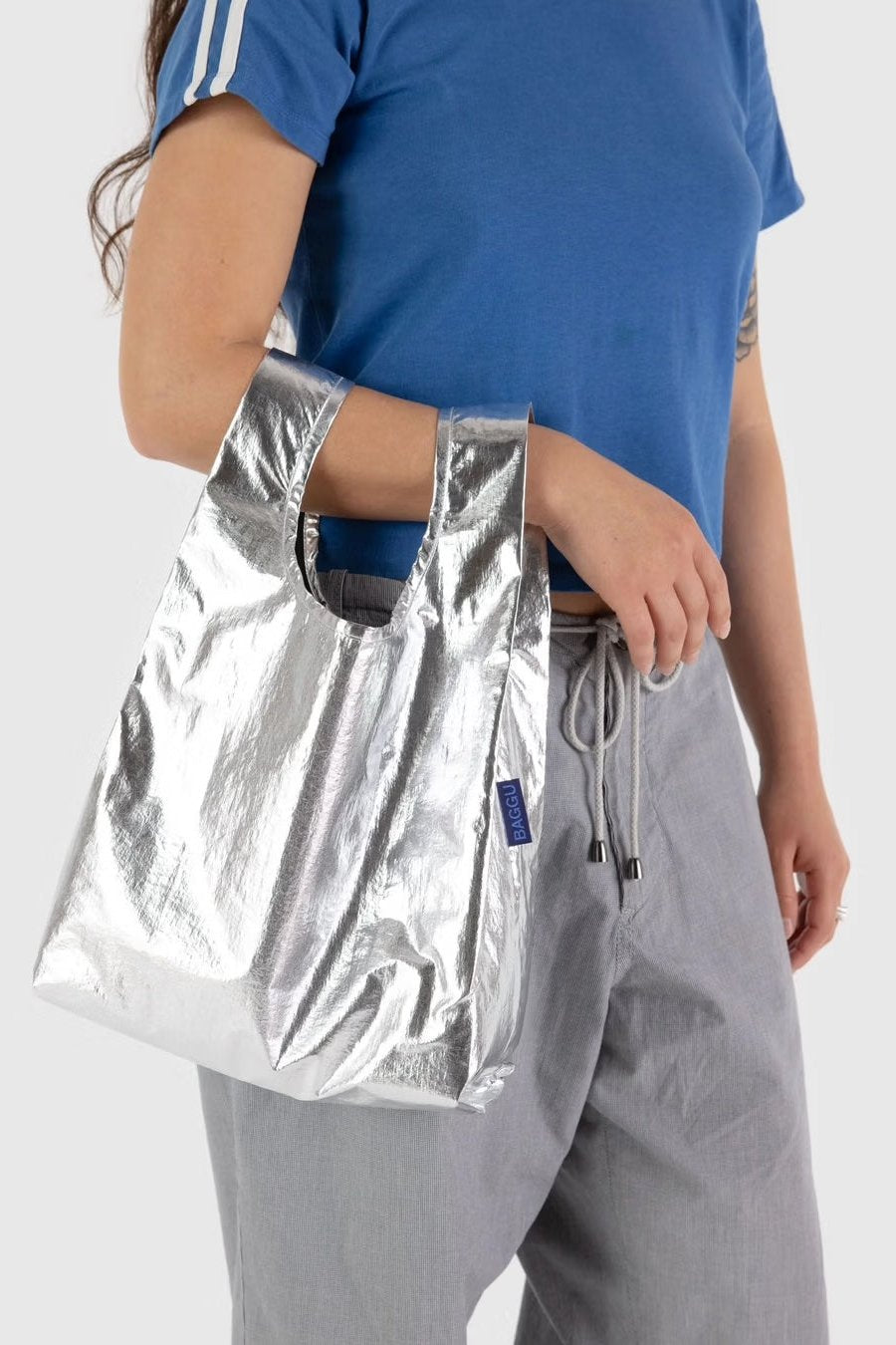 Baby BAGGU Tragetasche wird von einer dunkelhaarigen Frau am Arm getragen in der Trendfarbe metallic silver