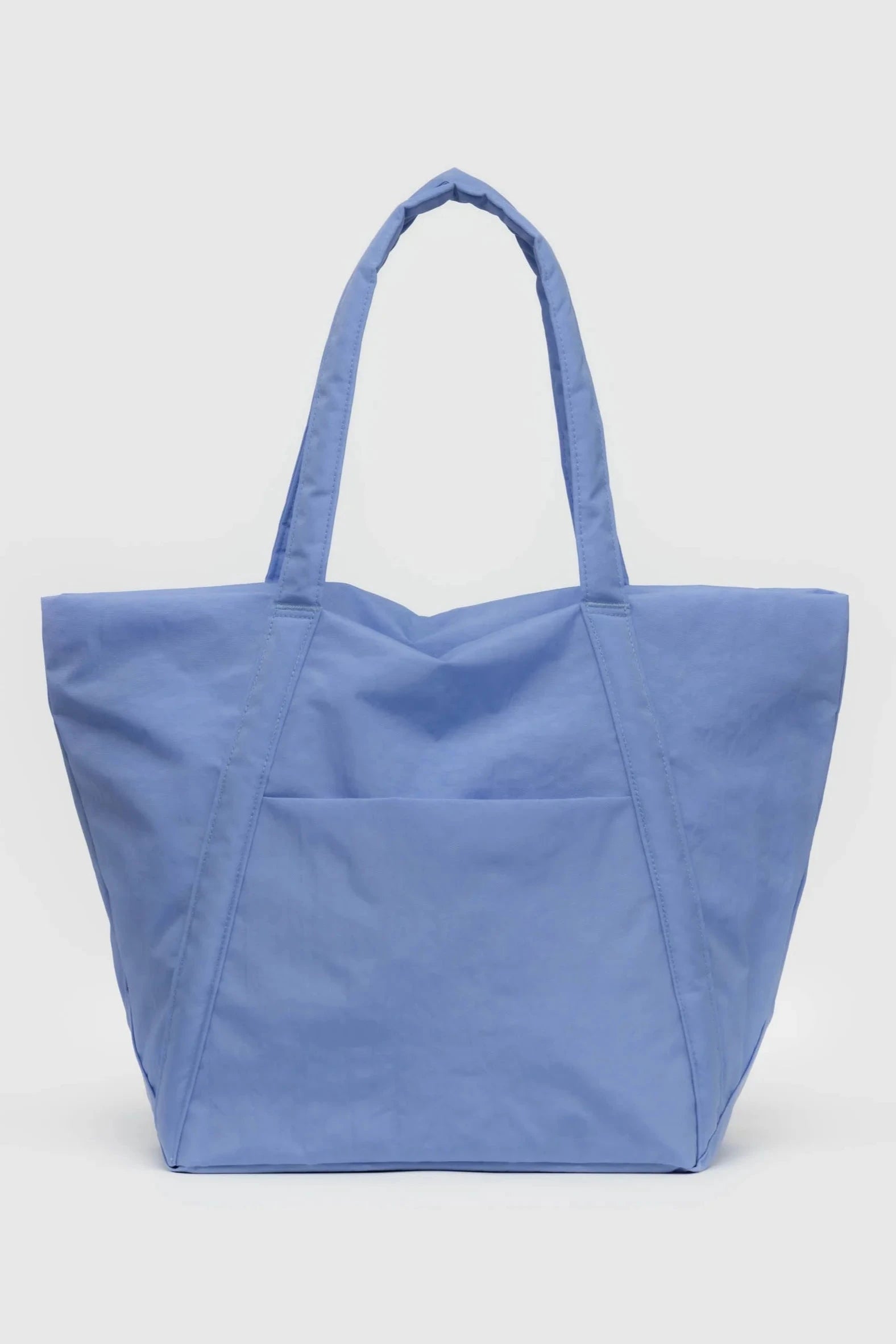 Die Main Design BAGGU Cloud Bag ist eine geräumige, hellblaue Tragetasche mit minimalistischem Design. Sie wurde von einem umweltbewussten Unternehmen aus recyceltem Nylon hergestellt und verfügt über zwei lange Griffe zum Tragen über der Schulter und eine große Vordertasche für zusätzlichen Stauraum. Die Tasche wird vor einem schlichten weißen Hintergrund präsentiert.