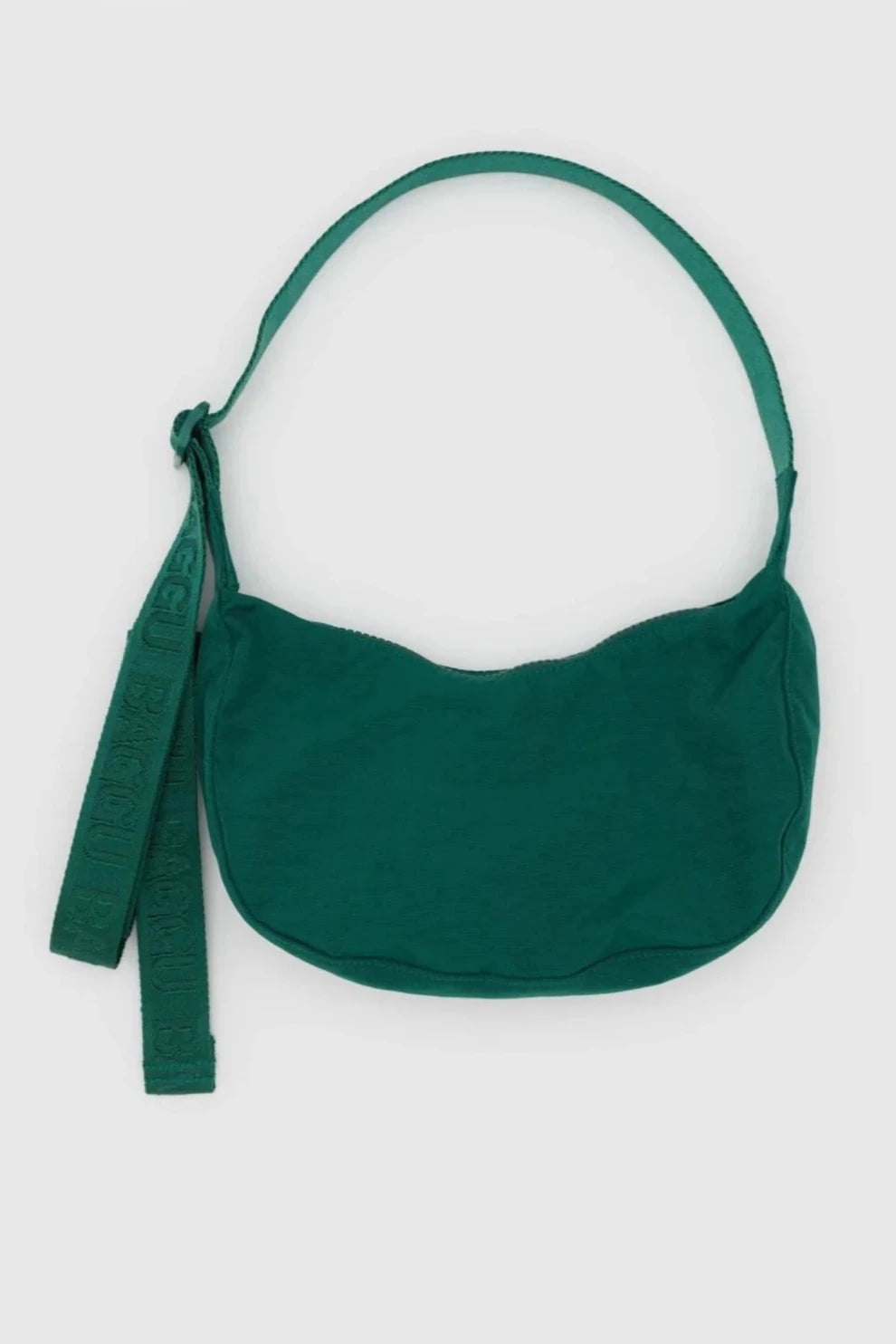 Eine kompakte grüne BAGGU Small Nylon Crescent Bag von Main Design mit einer weichen, geschwungenen Form. Sie verfügt über einen breiten Schultergurt und einen zusätzlichen dekorativen Gurt mit geprägtem Text, beide in passendem Grün. Die Handtasche wurde von einem umweltbewussten Unternehmen aus recyceltem Nylon hergestellt und ist vor einem schlichten weißen Hintergrund zu sehen.