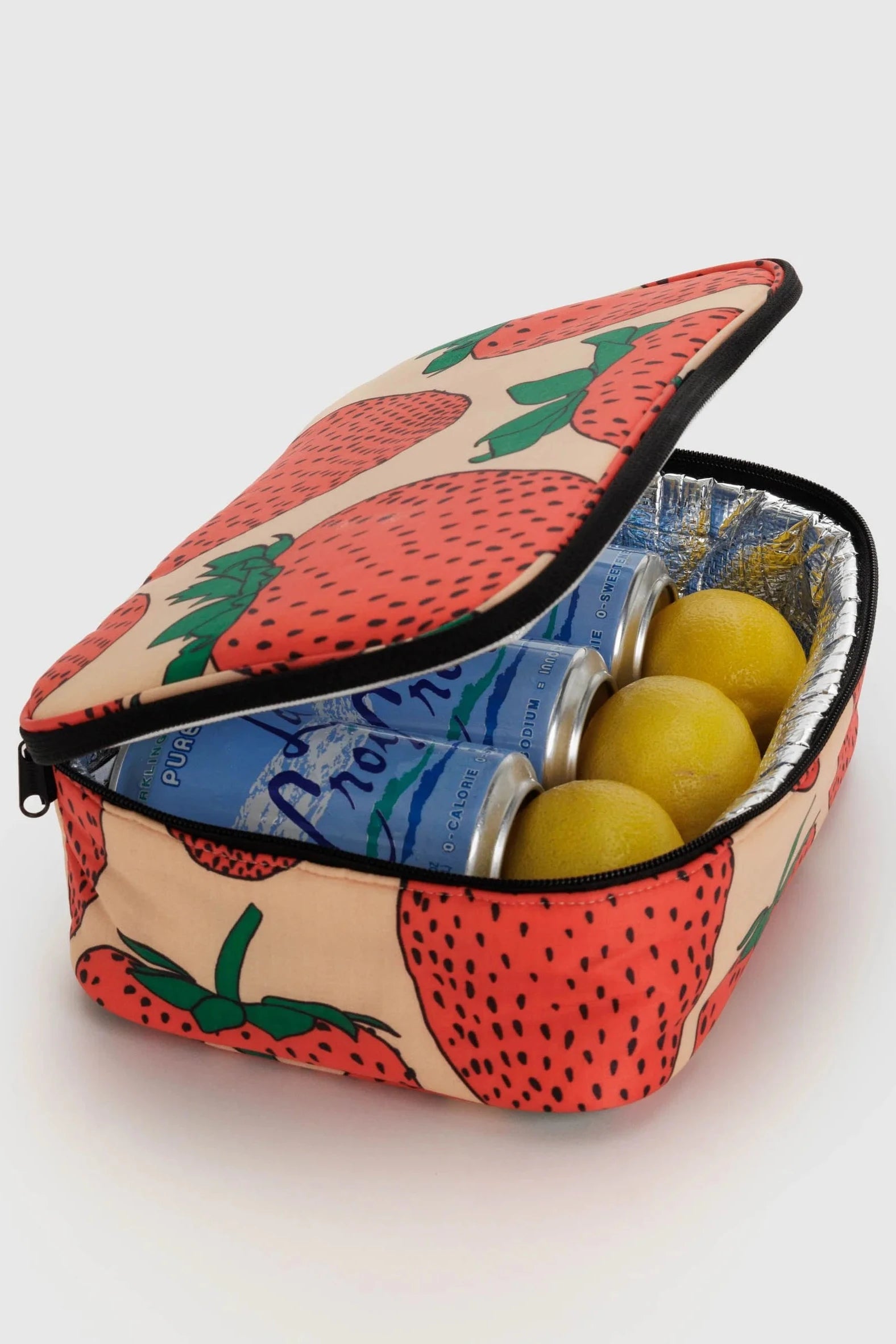 Eine Main Design BAGGU Lunchbox mit fruchtigem Erdbeer-Muster und teilweise geöffnetem Reißverschluss, der zwei Dosen LaCroix Mineralwasser und drei Zitronen im Inneren freigibt. Das Innere der Box ist mit reflektierendem Thermomaterial ausgekleidet.