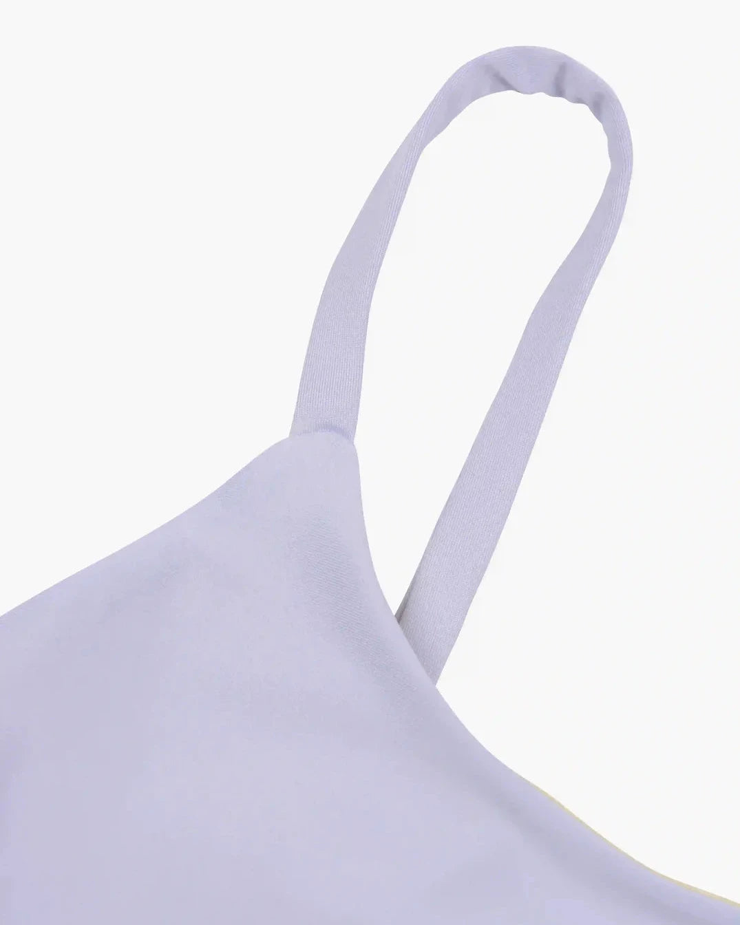 Nahaufnahme eines hellen lavendelfarbenen Spaghettiträgers an einem Sassy Bikini Oberteil Reversibel von Main Design vor einem schlichten weißen Hintergrund. Der aus nachhaltigen Materialien gefertigte Stoff wirkt glatt und leicht dehnbar.