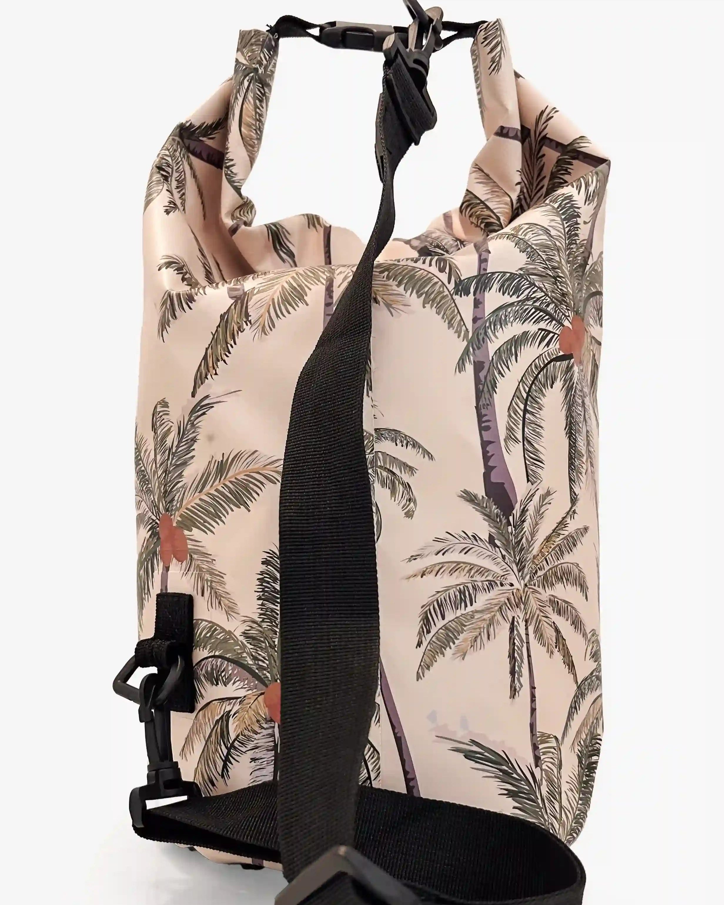 Der Dry Bag von Meraki Supply Co. by Main Design zeigt einen tropischen Palmendruck auf beigem Hintergrund. Er ist mit einem schwarzen verstellbaren Schultergurt, einem stabilen Schnallenverschluss an der Oberseite und einem gerollten Design zum Sichern und Verschließen Ihrer Reiseutensilien ausgestattet.