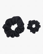 Zwei schwarze einfarbige Haargummis von Main Design sind auf einem schlichten weißen Hintergrund abgebildet. Ein Haargummi ist größer, der andere kleiner, beide bestehen aus gerafftem Stoff, der kreisförmige Formen bildet. Aus Stoffresten gefertigt, stellen sie eine stilvolle und dennoch nachhaltige Wahl für Ihre Haarschmuck-Kollektion dar.