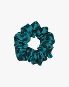 Der Haargummi gemustert von Main Design: Ein nachhaltiger, tealfarbener Scrunchie mit schwarzem Leopardenmuster aus Stoffresten, stilvoll präsentiert vor weißem Hintergrund.