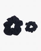 Zwei schwarze Haargummis aus recyceltem Stoff sind auf weißem Hintergrund platziert. Ein Haargummi ist deutlich größer als das andere, wodurch ein Größenvergleich möglich wird. Beide Haargummis mini von Main Design haben eine geraffte, gekräuselte Optik.